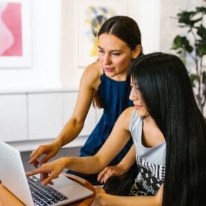 Two women are looking at a laptop screen.